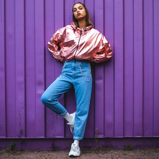 woman in pink zip-up jacket and blue denim jeans posing for a photograph