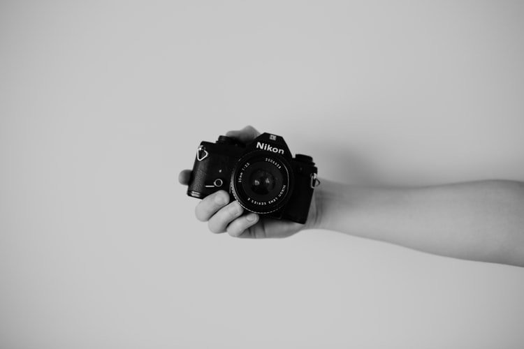 person holding a compact Nikon camera