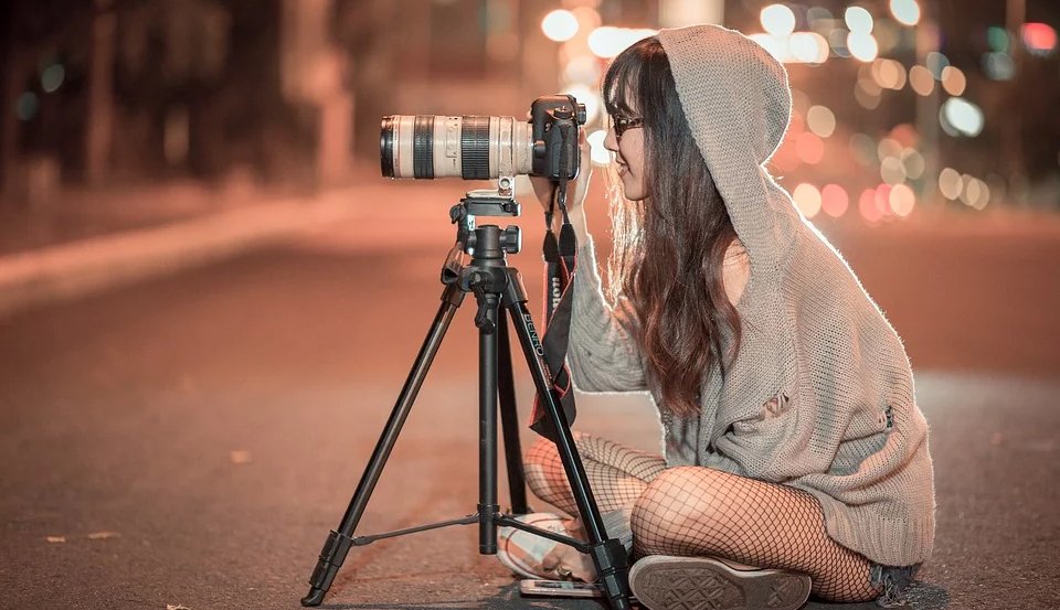a photographer sitting on the road with her camera