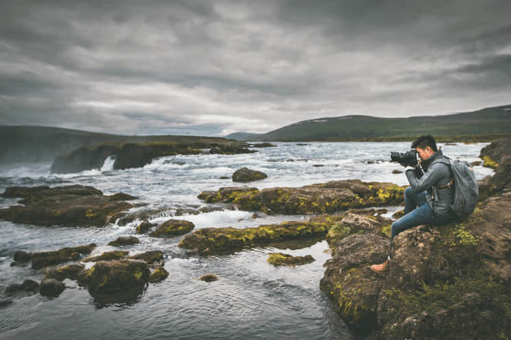a man near seashore taking a photo with his DSLR camera 