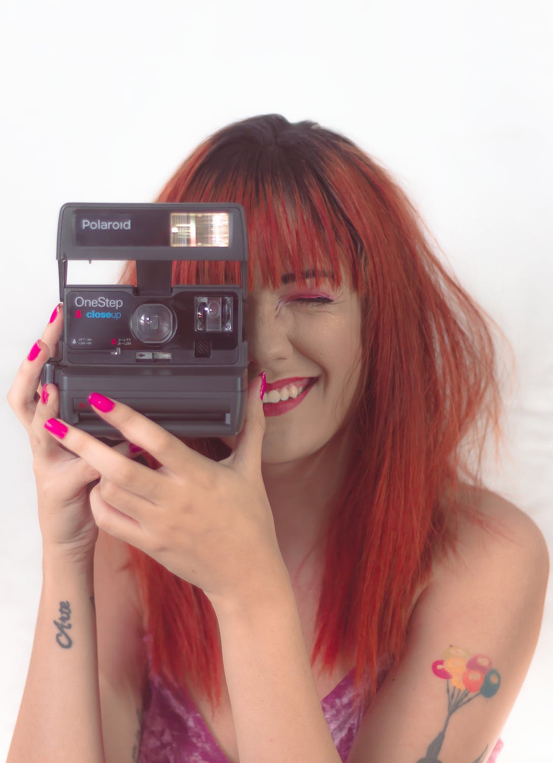 Woman Holding Polaroid Camera trying to focus on her subject