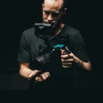 a man taking a video with some important gears attached to his video camera